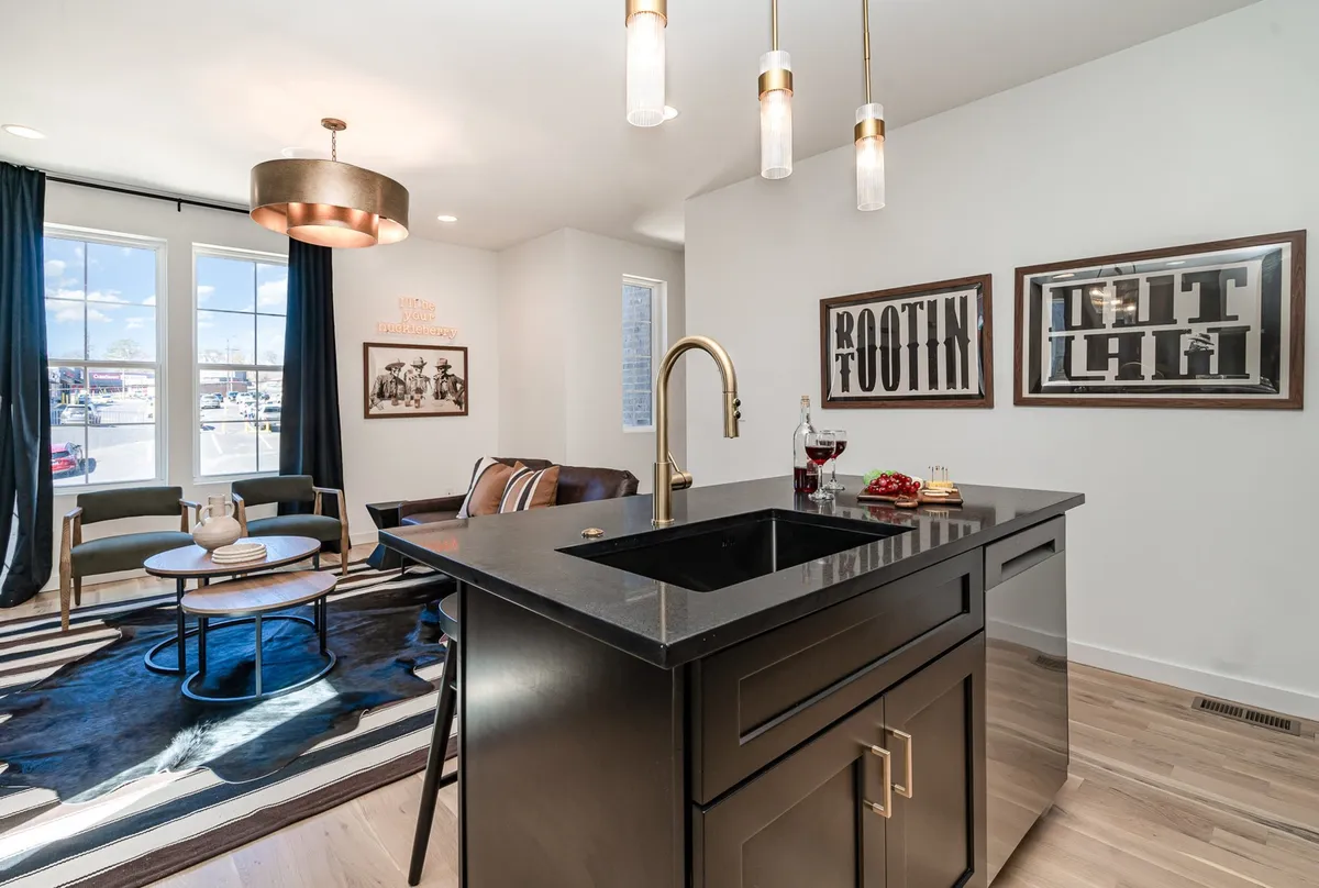 A contemporary kitchen and dining space with a central island, circular dining table, and expressive artwork on the walls. The room is filled with natural morning light, offering an inviting setting for everything from casual breakfasts to festive toasts.