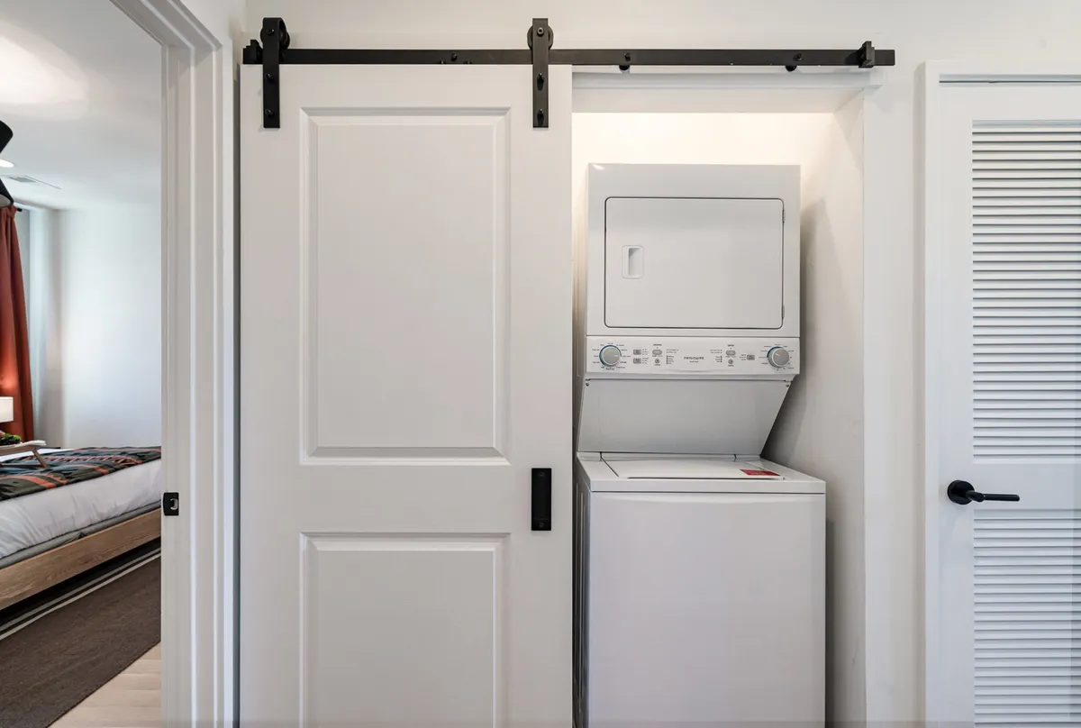 An interior shot of a laundry area featuring a washing machine, dryer, and a sliding barn door. The space looks clean, organized, and user-friendly, reflecting attention to practical hospitality details within the home.