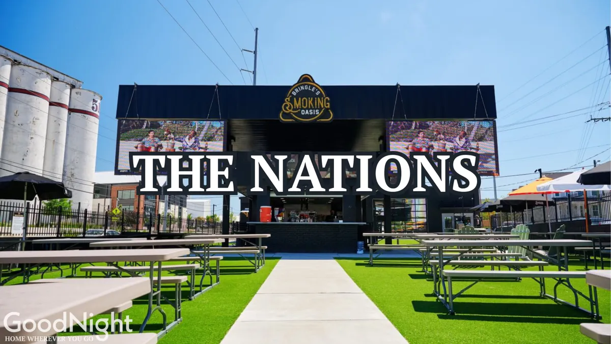 A vibrant, spacious outdoor seating area with prominent signage reading 'THE NATIONS,' featuring guests enjoying food and drinks. The area is festively decorated and designed for social gatherings and live events.