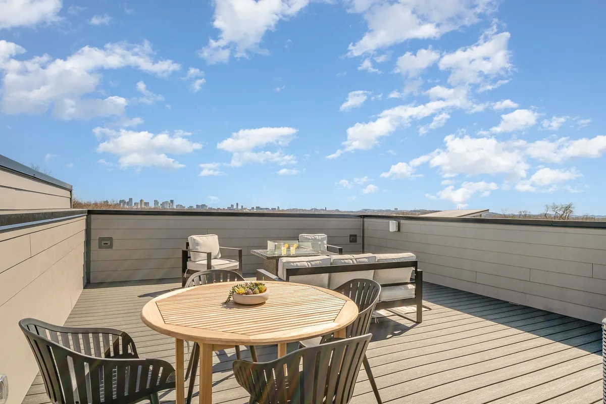 A rooftop deck with a chic outdoor seating area, dining table, and the Nashville city skyline in the background. The space exudes a serene and social atmosphere, perfectly suited for enjoying meals, cocktails, or quiet moments while taking in the urban vista.