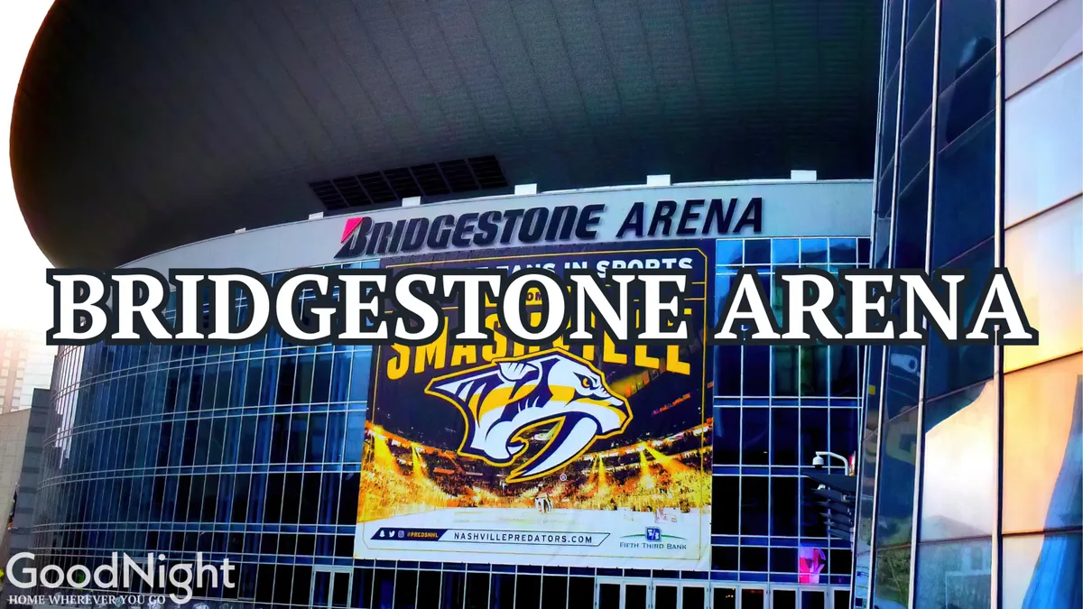 A dynamic exterior view of the Bridgestone Arena, featuring its iconic signage and a banner for the Nashville Predators, with the modern glass facade reflecting city lights. This area is known for hosting major concerts and events, drawing crowds to the heart of the entertainment district.