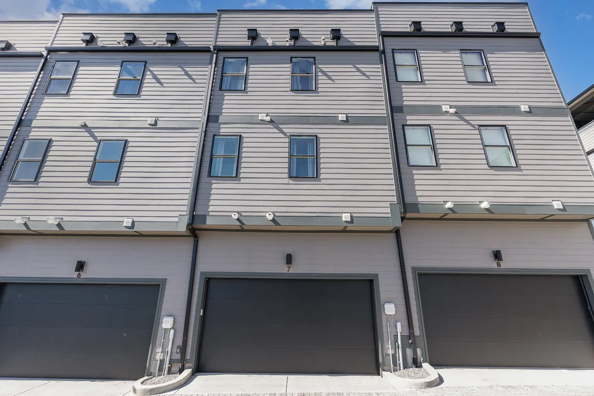 This exterior image showcases the modern architecture of Cadence homes, with a clear view of the garage doors and clean lines, emphasizing convenience and contemporary design. The photo highlights the private two-car garages for each home and the welcoming, community-oriented environment.