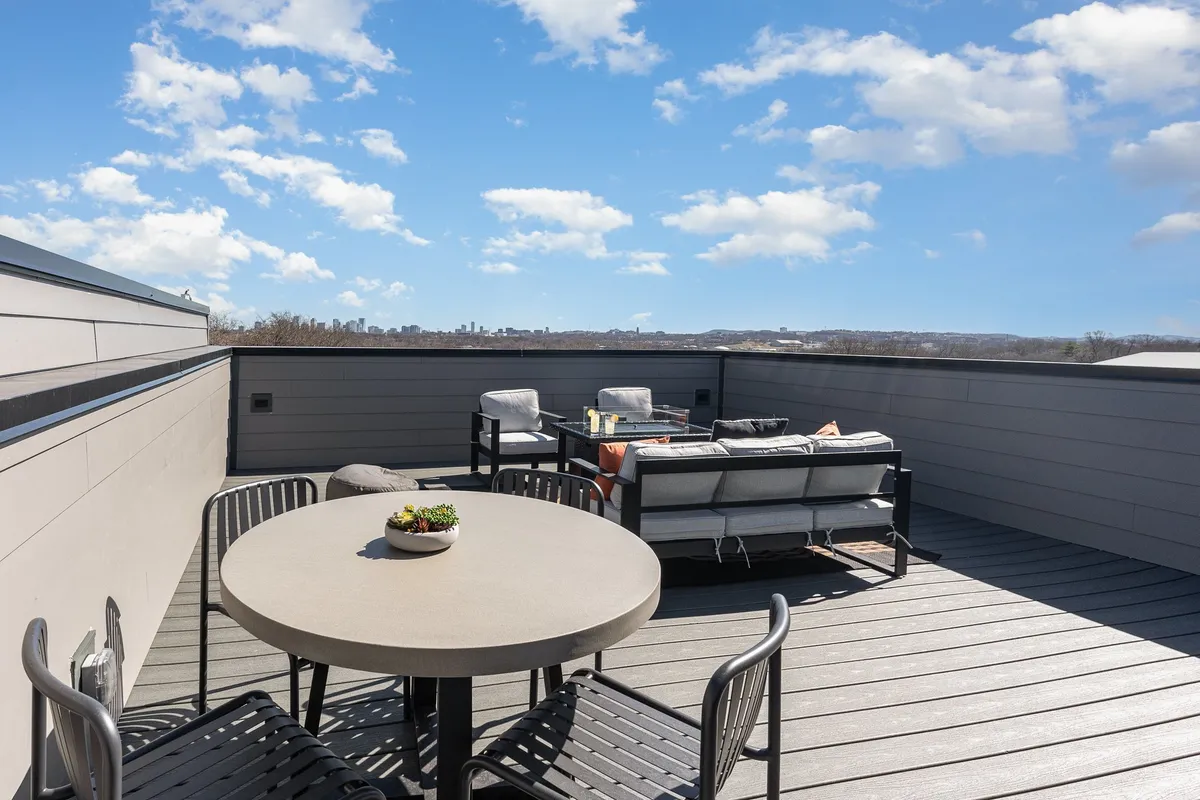A modern rooftop outdoor dining space with a dining table and city skyline view in the background. The ambiance is perfect for socializing, hosting barbecues, or enjoying sunset cocktails above the city.